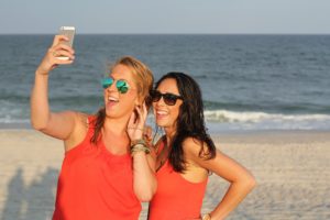 Beach buds wear same top for seaside selfies but sport their own unique sunglass styles.